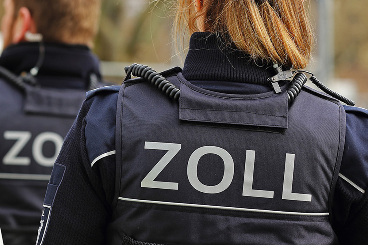 Zollermittlungen wegen Schwarzarbeit: Razzien und Kontrollen im Fokus Zwei Zollbeamte in dunkler Uniform, mit der Aufschrift