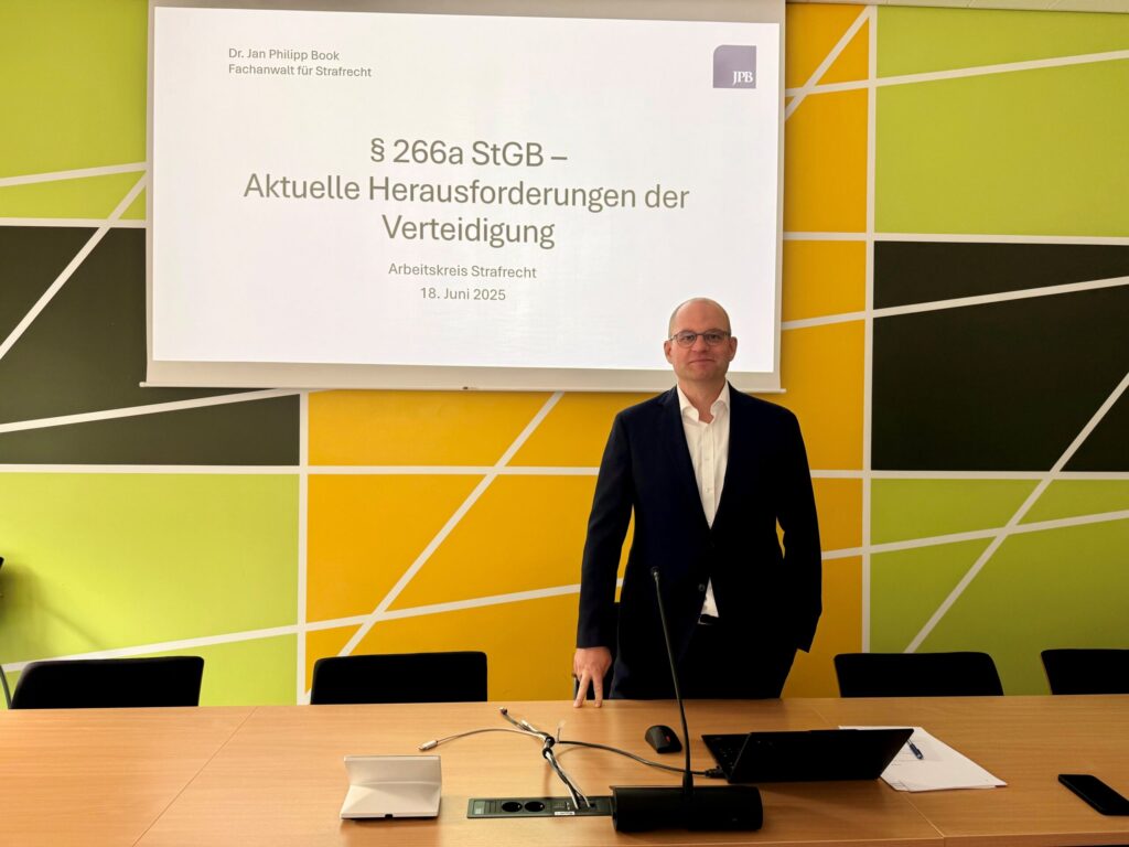 Vortrag von Dr. Jan Philipp Book zu § 266a StGB – Aktuelle Herausforderungen der Verteidigung Fachanwalt Dr. Jan Philipp Book steht vor einer Präsentationsfolie zum Thema § 266a StGB und spricht über aktuelle Herausforderungen der Verteidigung.